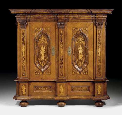 HALL CUPBOARD,Baroque, probably Erfurt circa 1720. Walnut, burlwood, cherry and local fruitwoods in veneer, very finely inlaid with figures, flowers, leaves and frieze. With stepped overhanging cornice and corresponding tall plinth and bun feet. The architectural style double door front with panels, uprights and finely carved capitals. Finely engraved brass mounts and iron lock. 192x75x208 cm. Provenance: Private collection, Germany. A similar cabinet is illustrated in: G. Nagel, Möbel, Augsburg 1991; p. 102f. (ill.134).