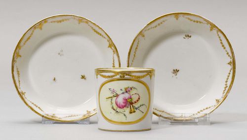 2 CUPS AND SAUCERS WITH TROPHY DECORATION,Nyon, ca. 1781-1813. 'Litron' form, painted with oval medallions with emblematic decoration. Rim with gold garlands. Underglaze blue fish marks. Gilding rubbed. Provenance: Private collection, Geneva.