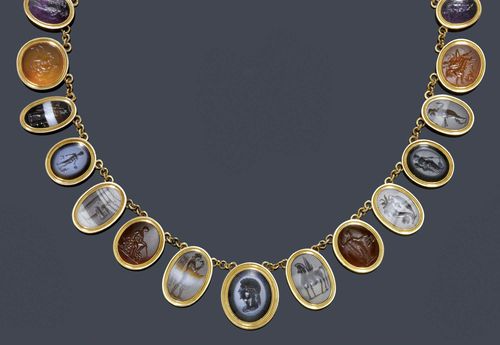 AN ANTIQUE GEMSTONE NECKLACE, circa 1860. Pink gold. Delicate necklace of 24 oval graduated gemstones: carnelian, agate, chalcedony, onyx, amethyst etc, with animal and mythological motifs, 4 - 5 gemstones probably antique, linked by sections of trace link chain. Oval agate clasp with an engraved inscription in Greek "Eros". L 36 cm.