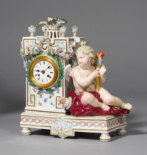 PORCELAIN MANTLE CLOCK WITH CUPID,Meissen, ca. 1880. Rectangular with flowers and leaf garland, crowned by 2 turtledoves on a rectangular base on which Cupid is seated with a torch. Underglaze blue sword mark.  Model number F 36 incised, painter’s number 12 in iron red. 30x23x13 cm. Joint between the clock and base, repaired.