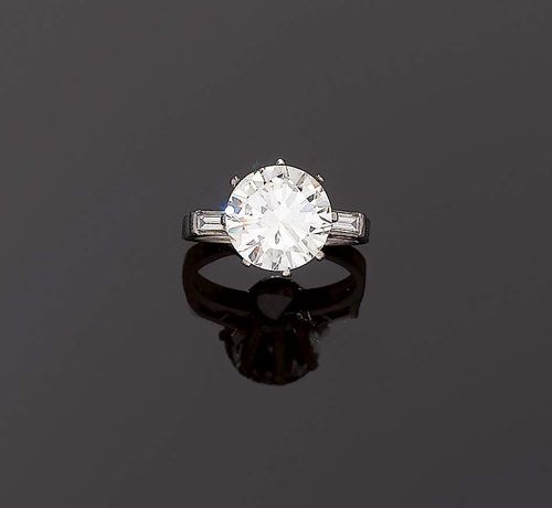 DIAMANT-RING, ca. 1950. White gold 750. Classic elegant solitaire model, set with 1 brilliant-cut diamond of 4.392 ct, tinted / VS1, flanked by 2 baguette-shaped diamonds totalling ca. 0.15 ct. Size 54. With SSEF Report No. 12411, April 2007.