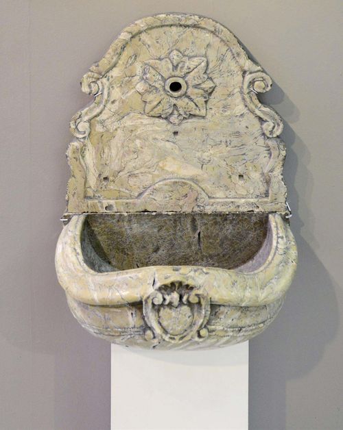WALL WELL,Baroque, probably Italy, 18th century. Brownish beige marble with cartouche. Consisting of a half-round basin with curved, moulded rim and a wall plate with rosette and opening for the spout. 60x40x78 cm.
