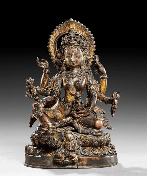 A FINE GILT COPPER FIGURE OF VASUDHARA ON A REPOUSSÉ LOTOS BASE. Nepal, 18th c. Height 15 cm. Surface slightly altered due to fire.