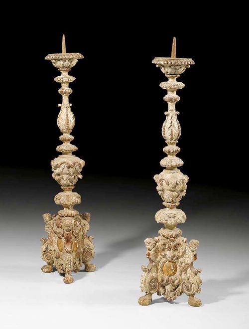PAIR OF PAINTED CANDLE HOLDERS,Baroque, German, 18/19th century Richly carved wood with putti, cartouches, flowers, leaves and frieze, painted in light grey and with traces of old gilding. H 99 cm. Provenance: Private collection, Brissago.