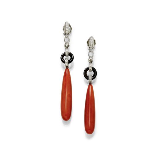 CORAL AND DIAMOND EAR PENDANTS. White gold 750. Attractive ear studs, each of 1 drop-cut coral of ca. 38.8 x 8.6 mm, flexibly mounted underneath 1 onyx ring held by eyelets set with diamonds. The stud part additionally decorated with diamonds. Total weight of the 20 diamonds ca. 0.20 ct. Two small eyelets in metal, silver-plated. L ca. 7.5 cm.