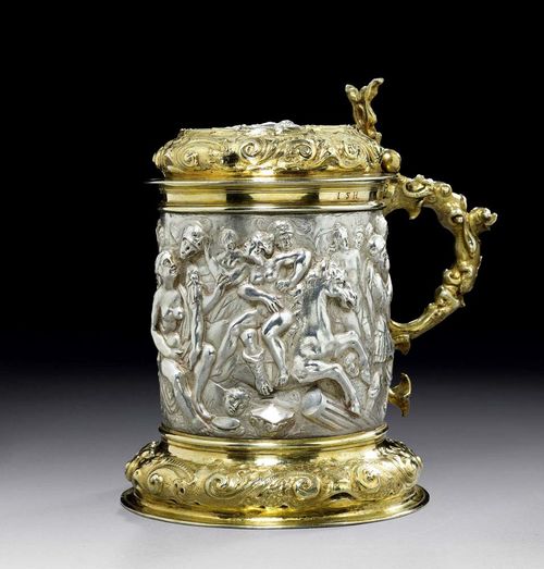 LARGE TANKARD AND LID parcel-gilt. Hamburg, 2nd half of the 17th century. Maker's mark  probably  Lambrecht. Chased foot with scrolls and rocaille, the body with figures in relief, the lid matching the foot and with inlaid silver relief. Large handle. H 22 cm. 1650 g.