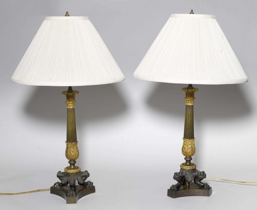 PAIR OF TABLE LAMPS,France, in the style of Charles X. Bronze with brown patina and parcel-gilt. Conical shaft, decorated with grooves and leaves. Beige fabric shade. H 70 cm. Fitted for electricity.