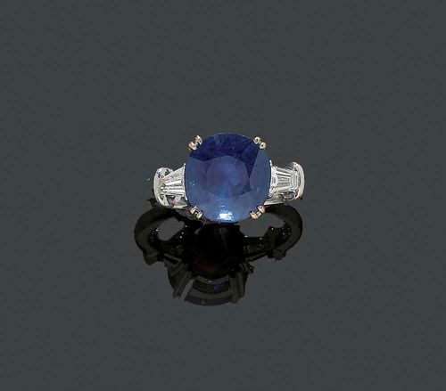 SAPPHIRE AND DIAMOND RING. White gold 750. Classic-elegant model, the top set with 1 slightly oval Burma sapphire of 6.02 ct, unheated, flanked by 2 trapeze-cut diamonds totalling ca. 0.40 ct. Size 53. With GRS Report No. GRS2007-063293, June 2007.