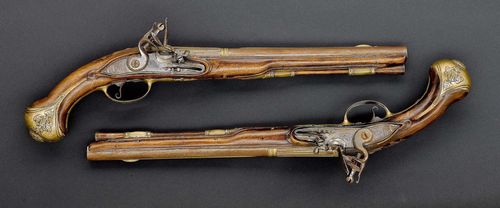 PAIR OF FLINTLOCK PISTOLS,1st half of the 18th century. Round barrel, octagonal chamber part (L 31.9 cm), Cal. 16 mm. Flat lock plate and cock, engraved with trailing flowers. Scrolled trigger guard. Carved walnut stock. Brass mount, decorated with a medusa head, putti and leaves. Wooden ramrod. Total length 49 cm.