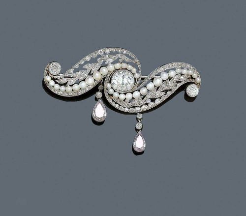 DIAMOND AND PEARL BROOCH, ca. 1910. Platinum. Charming brooch with volute motifs, set in the middle with 1 old mine cut diamond of ca. 1.90 ct, ca. G-H/P1. The florally open-worked surface is decorated with a line of small Oriental pearls and set with ca. 75 old mine cut and single-cut diamonds, totalling ca. 0.80 ct,  the lateral ends additionally set with 2 old mine cut diamonds totalling ca. 0.50 ct. The lower end consists of two movable pendants, each set with 1 diamond drop of ca. 0.40 and 0.55 ct, respectively, in fancy-pink. Mechanical part in white gold. With Gemlab Report No.1797/08.