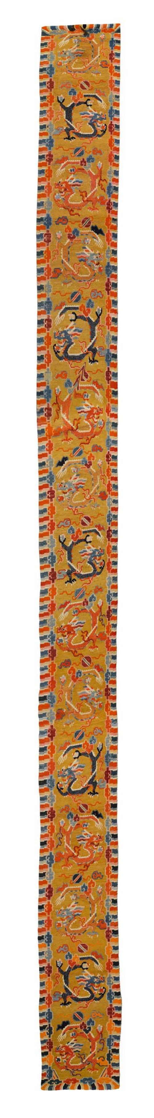 A WOOL RUNNER WITH POLYCHROME DRAGON MEDALLIONS ON AN OCHRE GROUND. Tibet, ca. 1920, 340x55 cm. Spots on the edge.