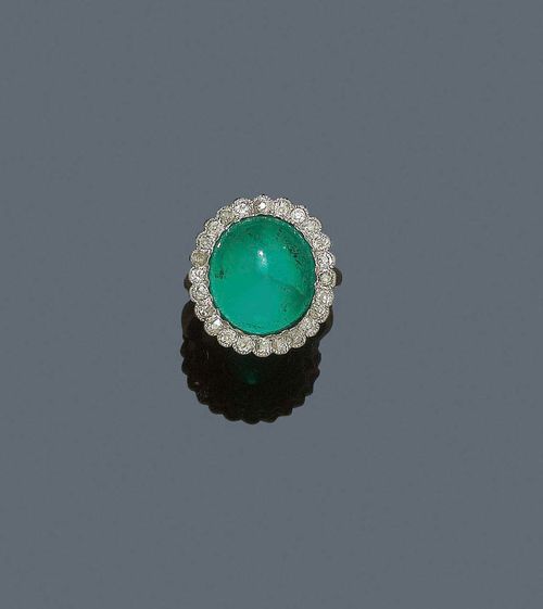EMERALD AND DIAMOND RING, ca. 1920. Platinum, shank in white gold. Very decorative "Entourage" model, the top set with 1 fine, oval, Columbian emerald cabochon of ca. 9.70 ct, untreated, surface with light signs of wear, surrounded by 24 old mine cut diamonds totalling ca. 0.50 ct. White gold shank, not original. Size 52. With Gemlab Report No. 1794/08.