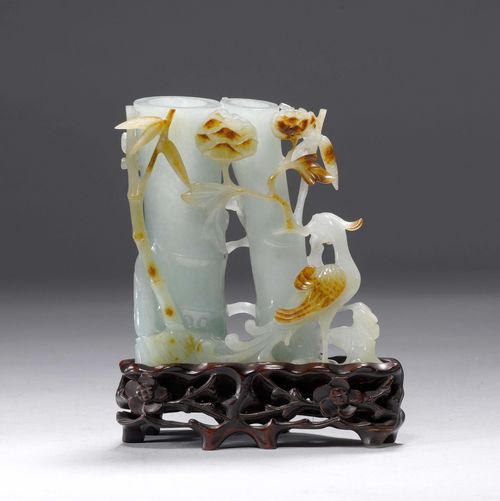 A LIGHT GREEN JADE BRUSH HOLDER CARVED IN THE FORM OF TWO SMALL BAMBOO STALKS, WITH PEONY BRANCHES, LINGZHI FUNGUS AND TWO PHOENIXES. China, Height 12 cm. Brown inclusions. Wood base.