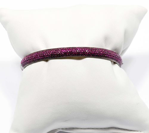 RUBY BANGLE. Silver, in part gold-plated. Set throughout with numerous rubies weighing ca. 7.00 ct. Ca. 5.5 x 4.5 cm.