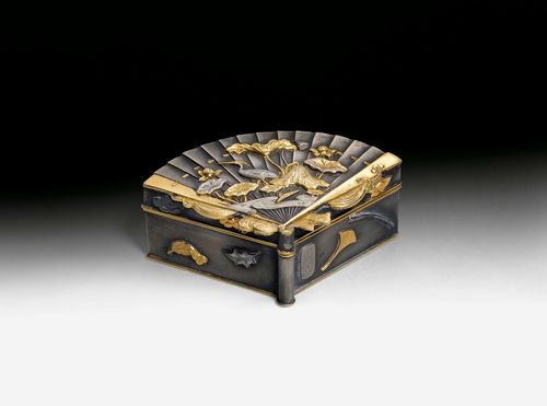 A SMALL FAN-SHAPED METAL BOX WITH GOLD AND SILVER ADDITIONS SHOWING A LOTUS POND WITH CRANE ON THE LID AND LEAVES ON THE SIDES. Japan, Meiji period, 2x5.5x3.5 cm. Signature in cartouche.