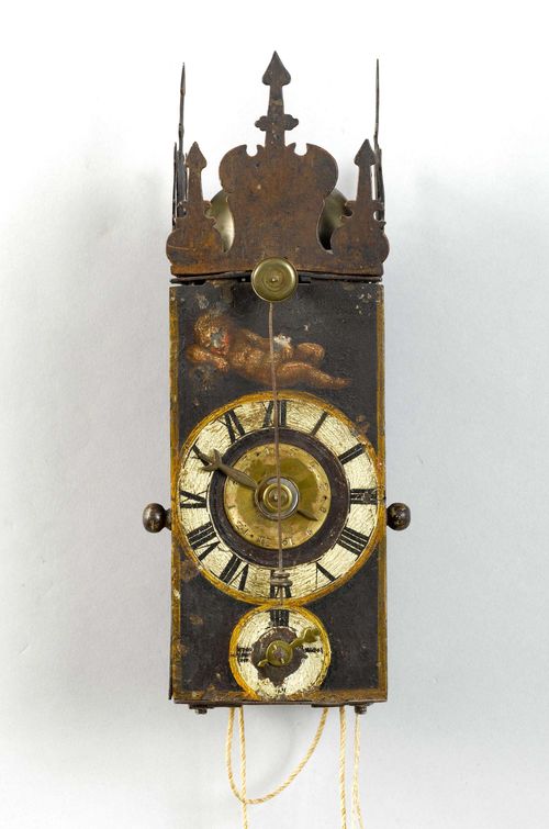 IRON CLOCK WITH FRONT PENDULUM AND ALARM,Baroque, Switzerland or Germany, 17th century. Closed metal case, painted with a reclining putto and 2 depictions of saints on the lateral doors. Pierced top. Painted dial with alarm disk, dial for the minutes below. Clockwork mechanism and striking mechanism arranged one behind the other. Movement with verge escapement striking the 1/2-hour on bell. Alarm on bell. H 26 cm. Painting, rubbed. Movement with alterations.