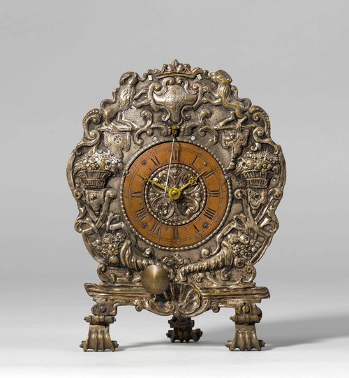 TABLE CLOCK WITH FRONT ZAPPLER,Baroque, Southern Germany, probably Augsburg, beginning of the 18th century. Brass sheet metal chased with baskets with flowers, cornucopias, volutes and a coat-of-arms held by lions, and silver-plated. Copper dial ring. Movement with verge escapement. H 26 cm. Silver-plating, rubbed. Provenance: - from a Zurich private collection.