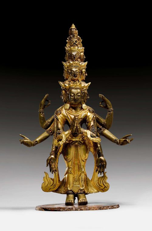 A BRONZE ELEVEN-HEADED FIGURE OF AVALOKITESHVARA, PARTIALLY GILT. Tibeto-Chinese, 19th c., height 16.5 cm. Glued to a stone plate. Attributes lost.