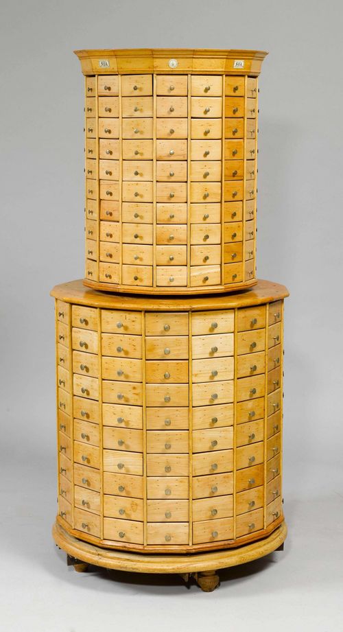 CHEST OF DRAWERS FOR A STORE,&quot;Noa&quot; model, La Chapelle, Kriens Lucerne, beginning of the 20th century. Beech, cylindrical, turnable two-part body on spherical feet. Upper part and lower part, each with 160 drawers. Different brass knobs. H 186 cm, D 85 cm. Restored.