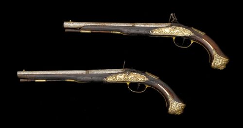 PAIR OF FLINTLOCK PISTOLS,German, ca. 1740. Round barrel (L 31.3 cm), Cal. 14 mm, octagonal chamber. Cock (broken) and flat lock plate, engraved with figures. Walnut stock, carved with tendrils, brass mounts with a hunting scene. Wooden ramrod.  Total length 49 cm. Requires restoration, some losses.