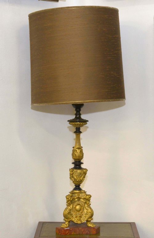 TABLE LAMP,Napoleon III. Bronze, gilt and blackened. Vase-shaped shaft decorated with heads of putti. Laurel, leaves and gadroons. Bronze, gilt and blackened. Red marble base, lion paw feet. H 60 cm. Brown fabric shade. Fitted for electricity.