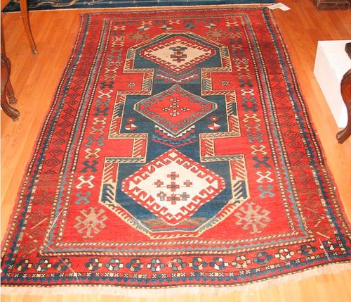 KAZAK old.Red ground with a blue central medallion, geometrically patterned, red border, slight wear, 225x130 cm.