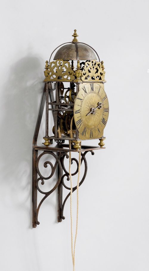 LANTERN CLOCK,Baroque, probably Germany or Holland, 17th/18th century. Rectangular, open iron case with pierced tendrils and bell on top, on spherical feet. Brass dial. Iron movement with brass cogwheels, verge escapement with short rear pendulum (probably later conversion), striking the 1/2-hour on bell. Repetition on demand. H 32 cm.