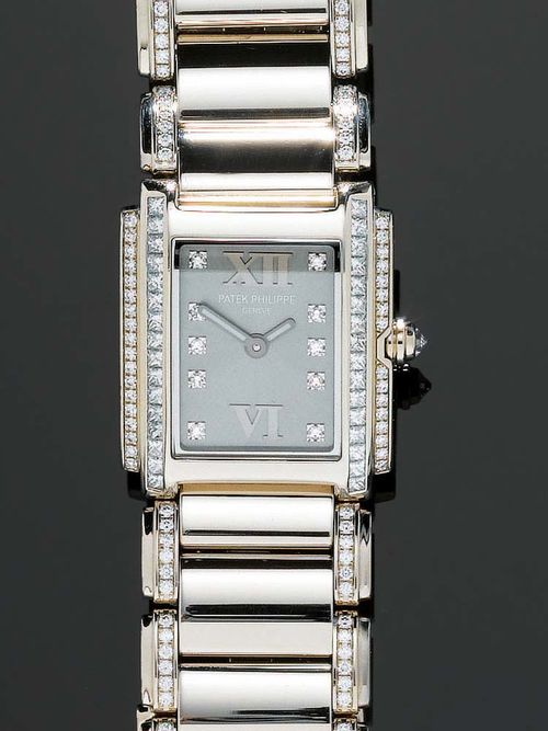 DIAMOND LADY'S WRISTWATCH, PATEK PHILIPPE TWENTY-4. White gold 750. Rectangular case No. 4173451 with 32 Princess-cut diamonds of 0.70 ct and 34 single-cut diamonds of 0.13 ct. Anthracite-coloured dial with 10 diamond indices and 2 silver-coloured numerals, light hands. Ref. 4908/37G-010, quartz movement, No. 3291601. Gold band with 205 brilliant-cut diamonds totalling 1.15 ct, fold-over fastener. Hardly worn, with case. Papers available.