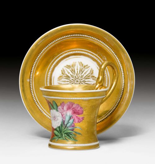 DISPLAY CUP AND SAUCER WITH SNAKE HANDLE,Berlin, Royal Porcelain Manufactory, ca. 1800. Conical cup with pearl frieze and snake handle. Gilt and opulently painted with a bouquet of carnations. Underglaze blue sceptre mark, impressed signs and numbers. H cup 7.5 cm. Gilding, partially rubbed.