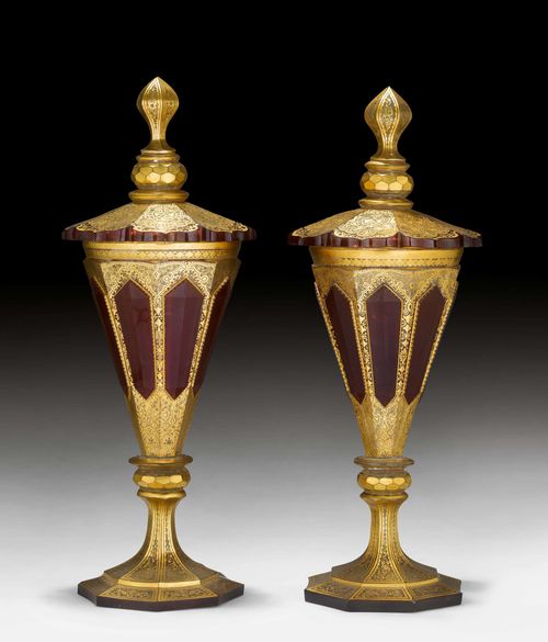 TWO LARGE GLASS LIDDED GOBLETS,Historicism, Bohemia, ca. 1880-1900. Transparent glass, tinted ruby red and decorated with gold arabesques. Curved, faceted cover with profiled finial. H 43 cm. (4) Provenance: - from a European collection.
