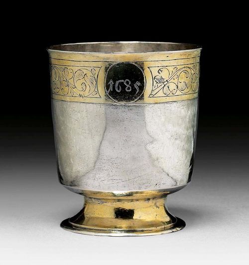 FOOTED BEAKER. Probably Frankfurt, 1st half of the 17th century.Probably Serary Matern (Serarius). Parcel-gilt. Smooth cylinder over a retracted round foot. Florally engraved decorative frieze on the upper rim. Engraving of initials and the year 1689. H 8 cm. 101 g. Minor repair on the foot.