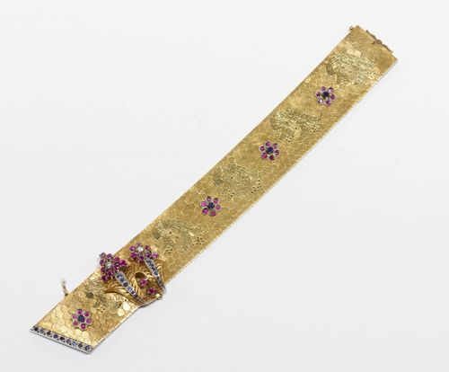 GEMSTONE AND GOLD BRACELET, ca. 1950. Yellow and white gold 750, 98 g. Satin-finished, "à ceinture" bracelet with a honeycomb pattern, decorated with 5 rosettes set with rubies and sapphires. Removable brooch with rubies, sapphires and 2 brilliant-cut diamonds weighing ca. 0.10 ct. W ca. 2.5 cm, L ca. 18.5 cm.