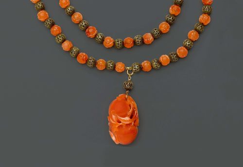A NECKLACE OF 75 CARNELIAN AND OPENWORK SILVER FILIGREE BEADS WITH DETACHABLE CARNELIAN PENDANT IN THE FORM OF TWO PEACHES WITH LEAVES. China, Length 74 cm, the pendant 5 cm.