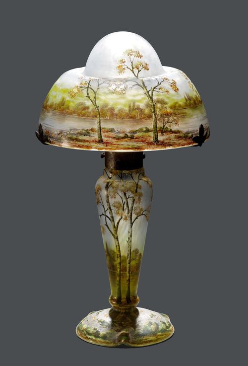 DAUM NANCY TABLE LAMP, c. 1900 Light blue glass, etched and enamelled. Mushroom-shaped, decorated with an autumn landscape. The foot signed Daum Nancy. H 35 cm.