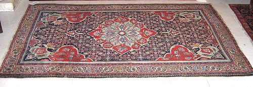 BIDJAR antique. Dark central field with floral central medallion finely patterned with stylised flowers. White border. Some wear, one side slightly shortened. 220x140 cm.