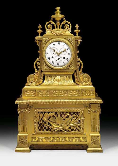 IMPORTANT CLOCK WITH ORGAN MUSICAL MOVEMENT, Louis XVI, the bronzes probably by J.J. LEMOYNE (Jean-Jacques Lemoyne, maitre 1772), Paris circa 1780. Matte and polished gilt bronze. The rectangular case with two-handled vase and fine scrolled applications, set on plinth containing the musical movement. The clock with enamel dial and 3 small chapter rings for days of the week, date and month. Fine verge escapement striking the 1/2 hours on 2 bells. The organ movement with cylinder, bellows and 17 tin pipes for 6 melodies on request. Requires some restoration. 41x26x75 cm. Provenance: from a European private collection