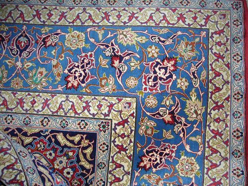 ISFAHAN. Red ground with blue corner motifs and blue and white central medallion, decorated with trailing flowers and palmettes, white border, good condition, 309x208 cm.