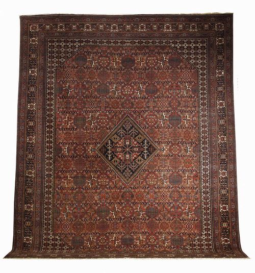 JOSHAGAN old. Dark red central field with rhombus shaped medallions in blue, the whole carpet with honeycomb pattern and stylised plant motifs, triple stepped border, slight wear, otherwise good condition, 410x320 cm.