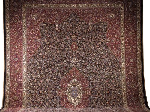 MESHED SABER, signed, ca. 1940. Attractive very finely knotted piece, white and red central medallion on blue ground with red corner motifs, the whole carpet finely decorated with trailing flowers and palmettes, broad border in red, good condition, 630x405 cm.