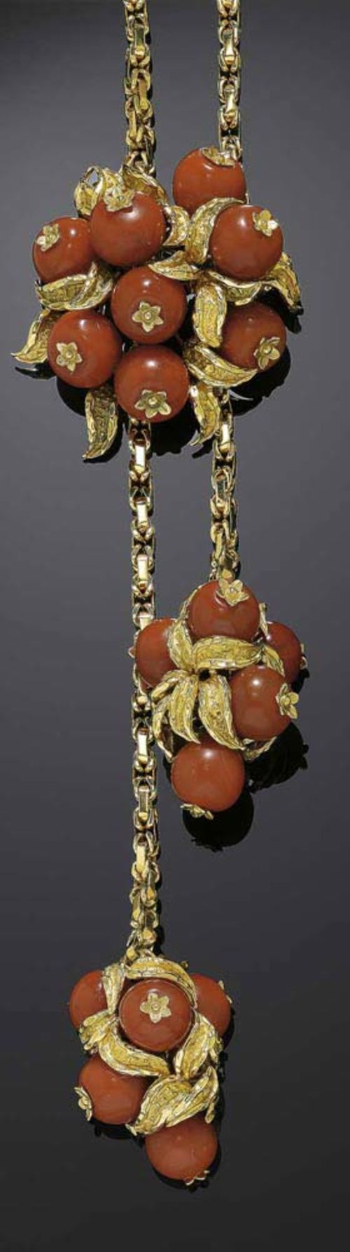 GOLD AND CARNELIAN SAUTOIR, E. MEISTER. Yellow gold 750. Highly decorative fantasy chain, both ends of which are made up of a cluster of 5 carnelian beads of ca. 12.5 mm Ø, between structured gold leaves. Large removable and adjustable latch in corresponding design, with 8 carnelian beads. L chain ca. 100 cm. Matches the following lot.