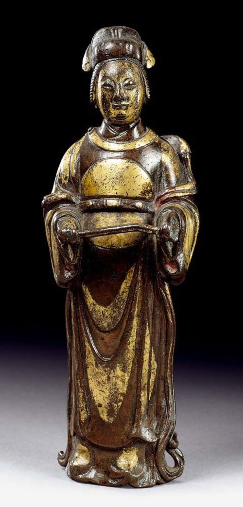 STANDING CIVIL SERVANT.China, Ming Dynasty, 15.5 cm. Finely-cast bronze with partial fire gilding and traces of red lacquer (on the inside of the sleeves). Finely-worked figure with nice contrasts, since the folds of the garment are alternately bronze and gold.