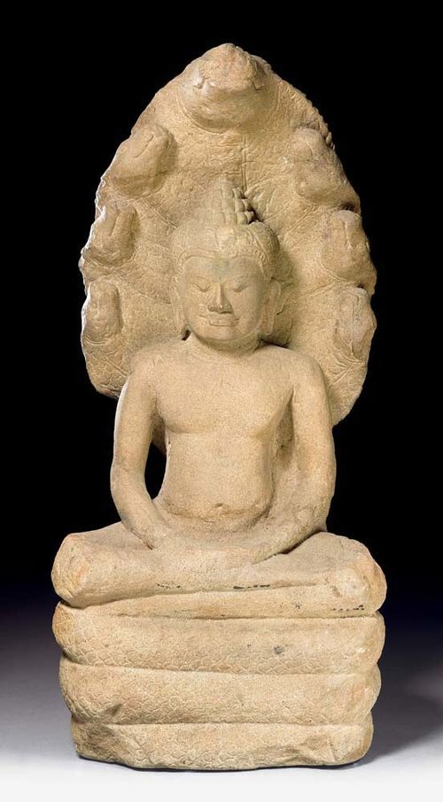 BUDDHA MUCHALINDA.Khmer, Lopburi, 13th century. H 71 cm. Sandstone. The Buddah is seated in a meditative posture on a coiled naga which is protecting and sheltering him with its seven heads. The downcast eyes and the meditative smile express contemplation and concentration. The carefully arranged hair is separated by a band, the only adornment of the Buddha. On the back: A delicate lotus rosette is positioned between the densely patterned scales on the canopy of snakes. From a private Swiss collection.