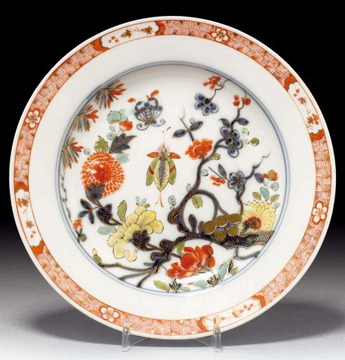 PLATE WITH BRANCH PATTERN, Meissen, circa 1735.Painted with spray of peonies and flowering prunus branches and butterflies in underglaze blue, iron red, green, sea green and yellow. With underglaze blue double ring and iron red lattice border, with reserves of flowering branches on the sides. Underglaze blue sword mark and painter's mark K. D 22 cm. The enamel colours and gilding slightly rubbed in places. Provenance: from a private collection, Solothurn