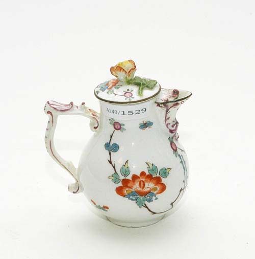 SMALL MILK JUG WITH KAKIEMON DECORATION, Meissen, circa 1740.With shaped handle and rocaille spout heightened in purple and painted with Indianische Blumen and bamboo stems. Underglaze blue sword mark. H 11cm. The spout and handle restored. Provenance: from a private collection, Solothurn