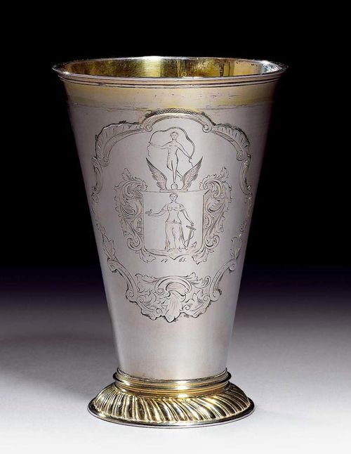 TALL BEAKER. Parcel-gilt. Riga, ca. 1765.Maker's mark Michale Kresnder the Younger. On a slightly convex, ribbed foot. Conical wall with a large coat-of-arms applied, with ornamental engraving and the year 1765. H 18 cm. 415 g. Provenance: Fritz Payer.
