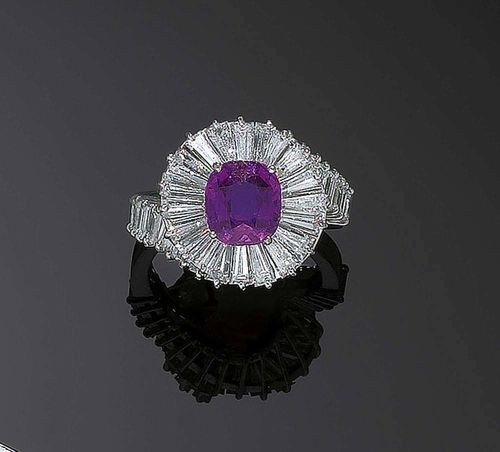 RUBY AND DIAMOND RING, ca. 1950. White gold 750. Fancy ring, the top is set with 1 antique oval ruby of ca. 2.75 ct, probably Burmese, untreated, signs of wear, in a spiral-shaped surround of numerous baguette-cut diamonds totalling ca. 3.40 ct. Size 52. With case.