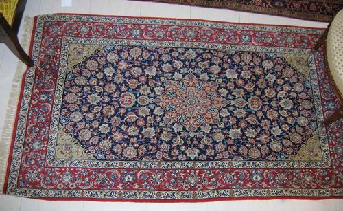 ISFAHAN. Blue ground with floral central medallion and light green corner motifs, decorated with trailing flowers and palmettes. Red border. Good condition. 108x183 cm.