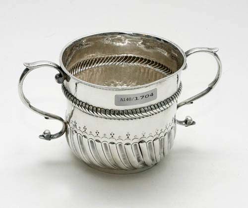 BEAKER WITH HANDLE. London, 1694. Maker's mark HC in the coat-of-arms, featuring 2 rings and a star. The lower rim with small convex and concave shafts, above a finely engraved bow, stars and points. H 9 cm. 200 g. The maker's mark originates from a London silversmith whose work has been known from 1693.