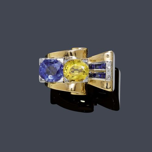 A DIAMOND AND SAPPHIRE RING, circa 1940. Pink and white gold. A fancy "à-pont" model, set with 1 yellow and 1 blue oval Ceylon sapphires weighing ca 4.00 ct and 6 square-cut sapphires and 3 baguette-cut diamonds. Size ca. 52.