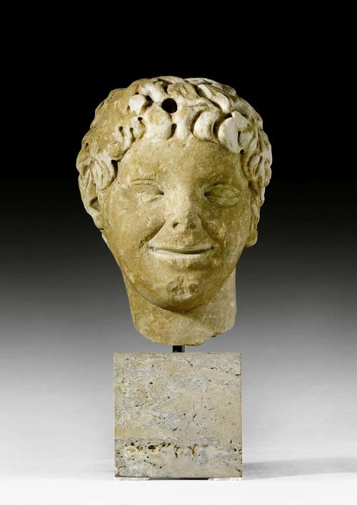 HEAD OF A FAUN,Roman, 2nd/3rd century AD. Light marble.  Mounted on a stone base. H without base 21 cm, with base 32 cm. Provenance: - Sam Dormont, Tel Aviv. - Swiss private collection, acquired 1980.